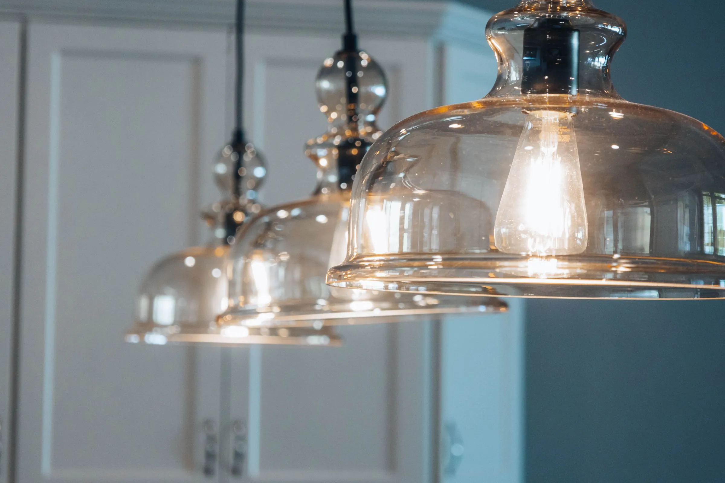 Warm glowing glass pendant lights freshly installed over a modern Perth kitchen
