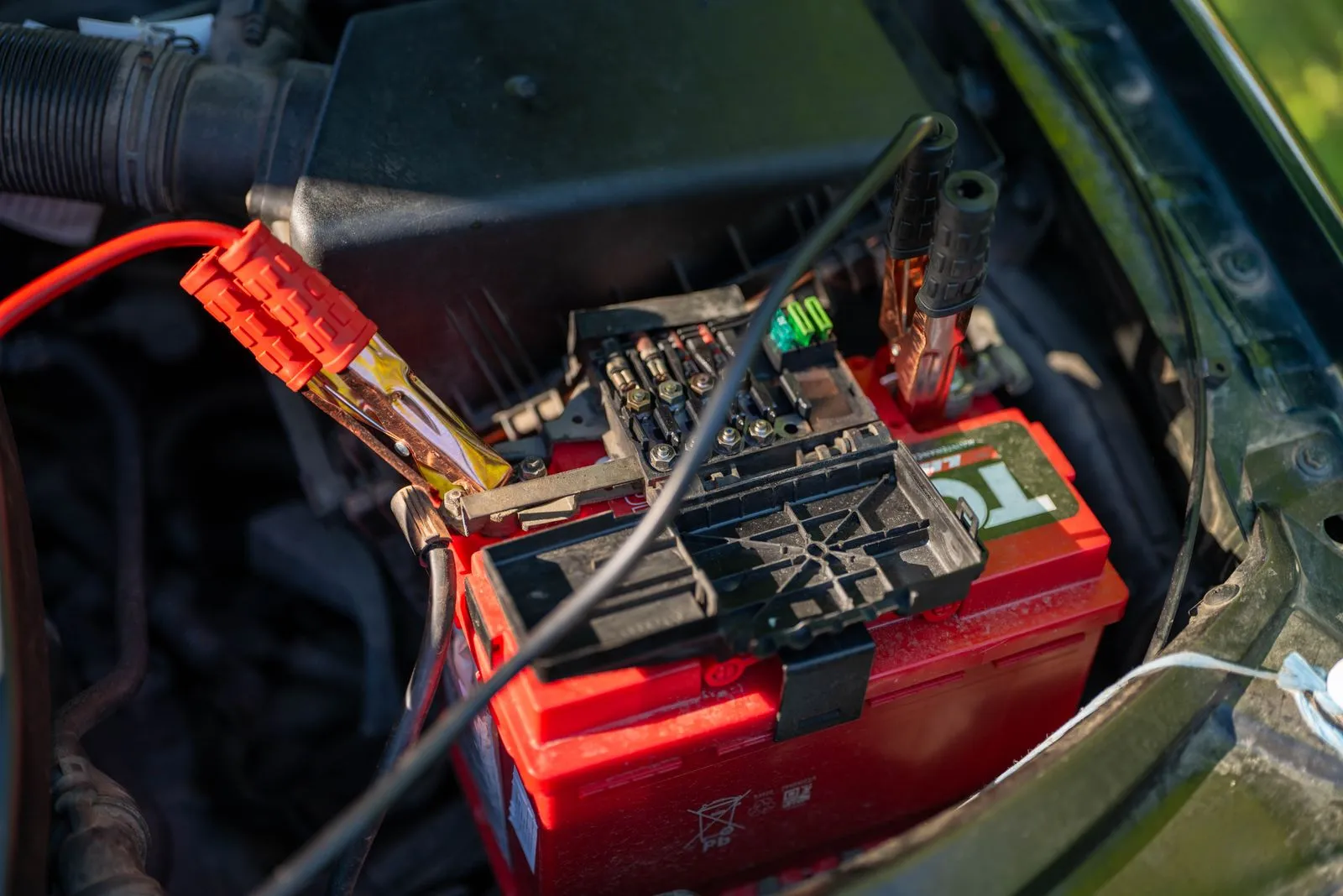 Car battery with jumper cables clamped on under the bonnet