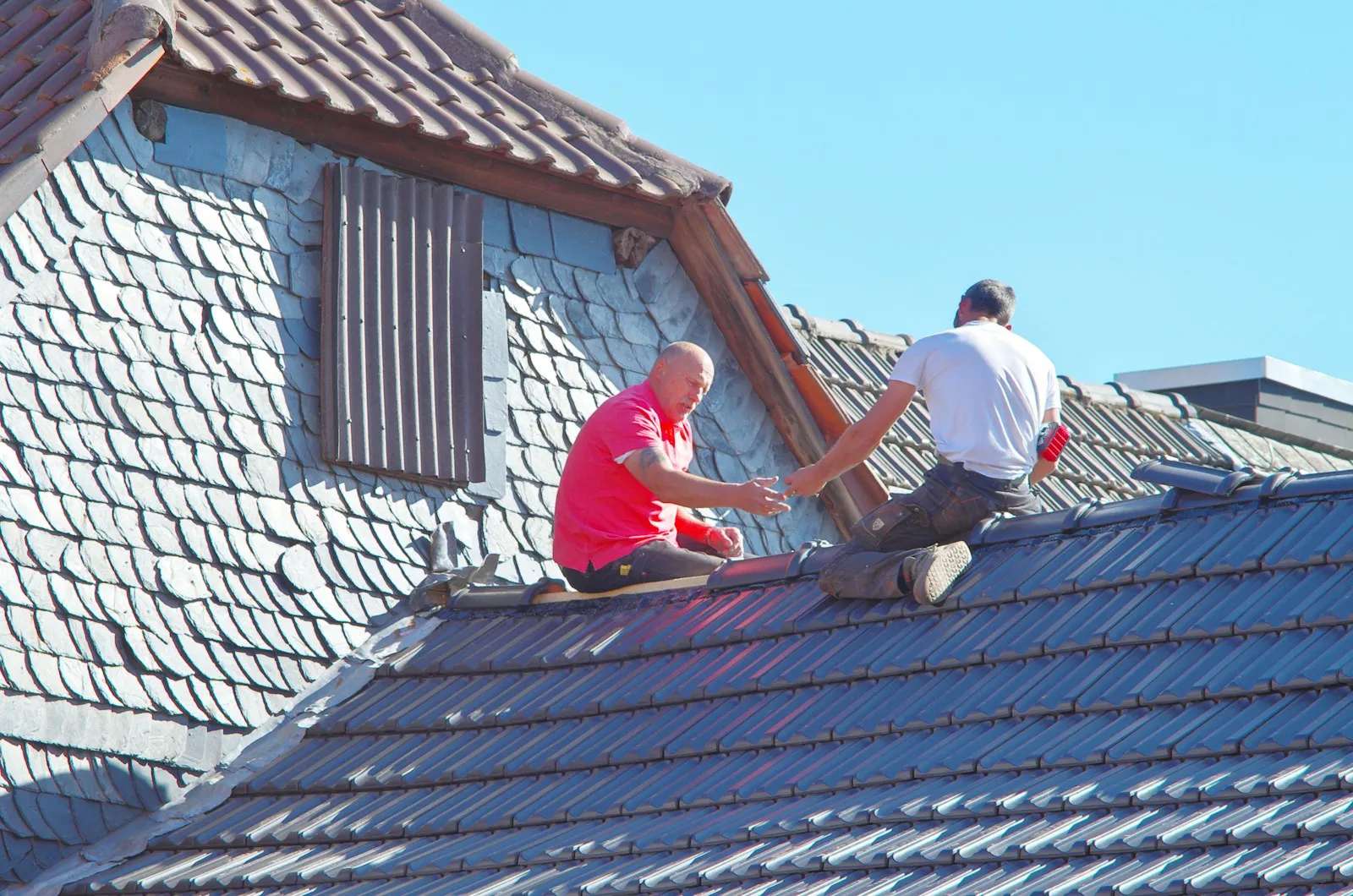 Roofer re-bedding and pointing ridge capping on a tile roof