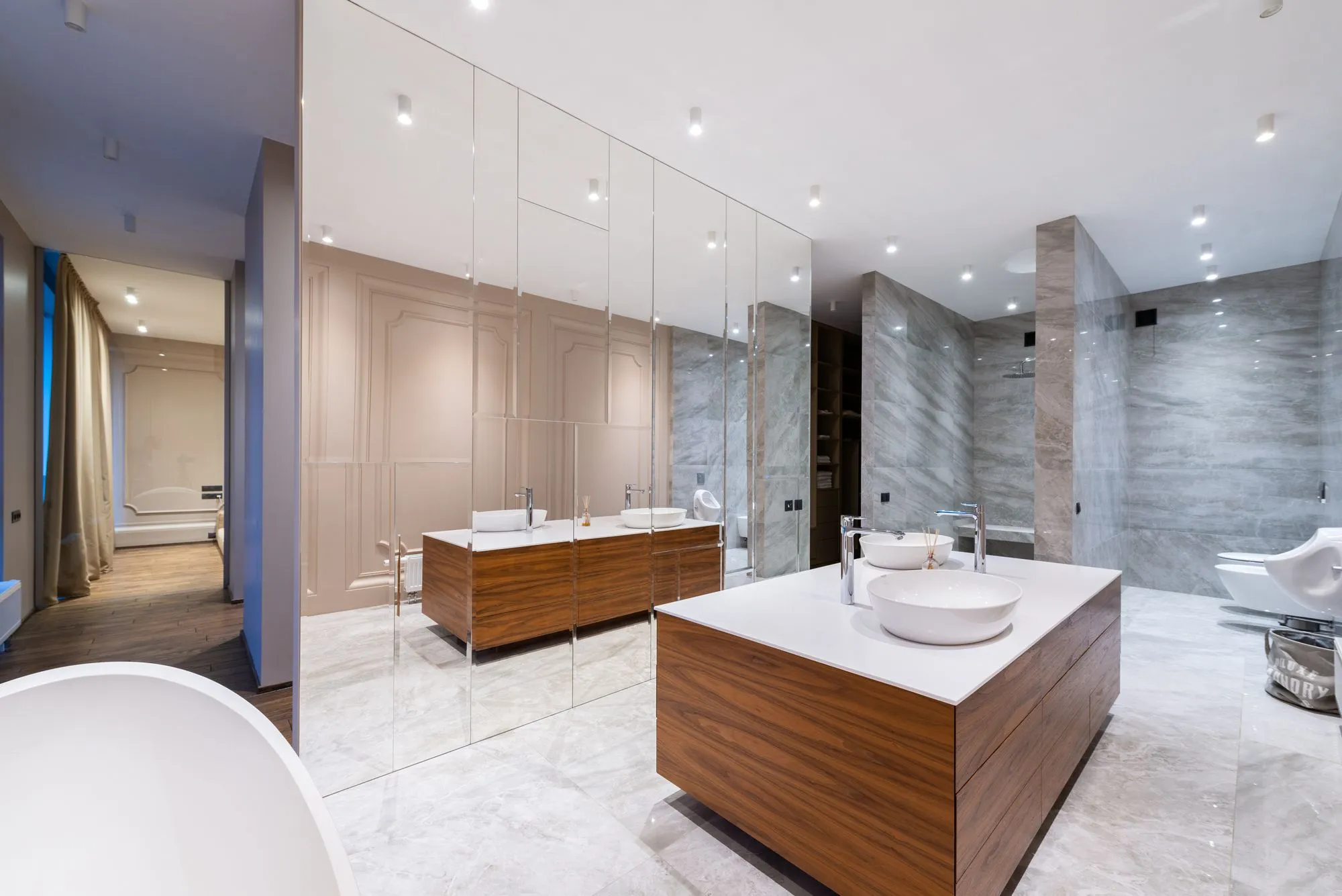 A wide luxury bathroom with a double stone vanity and floor to ceiling tiling