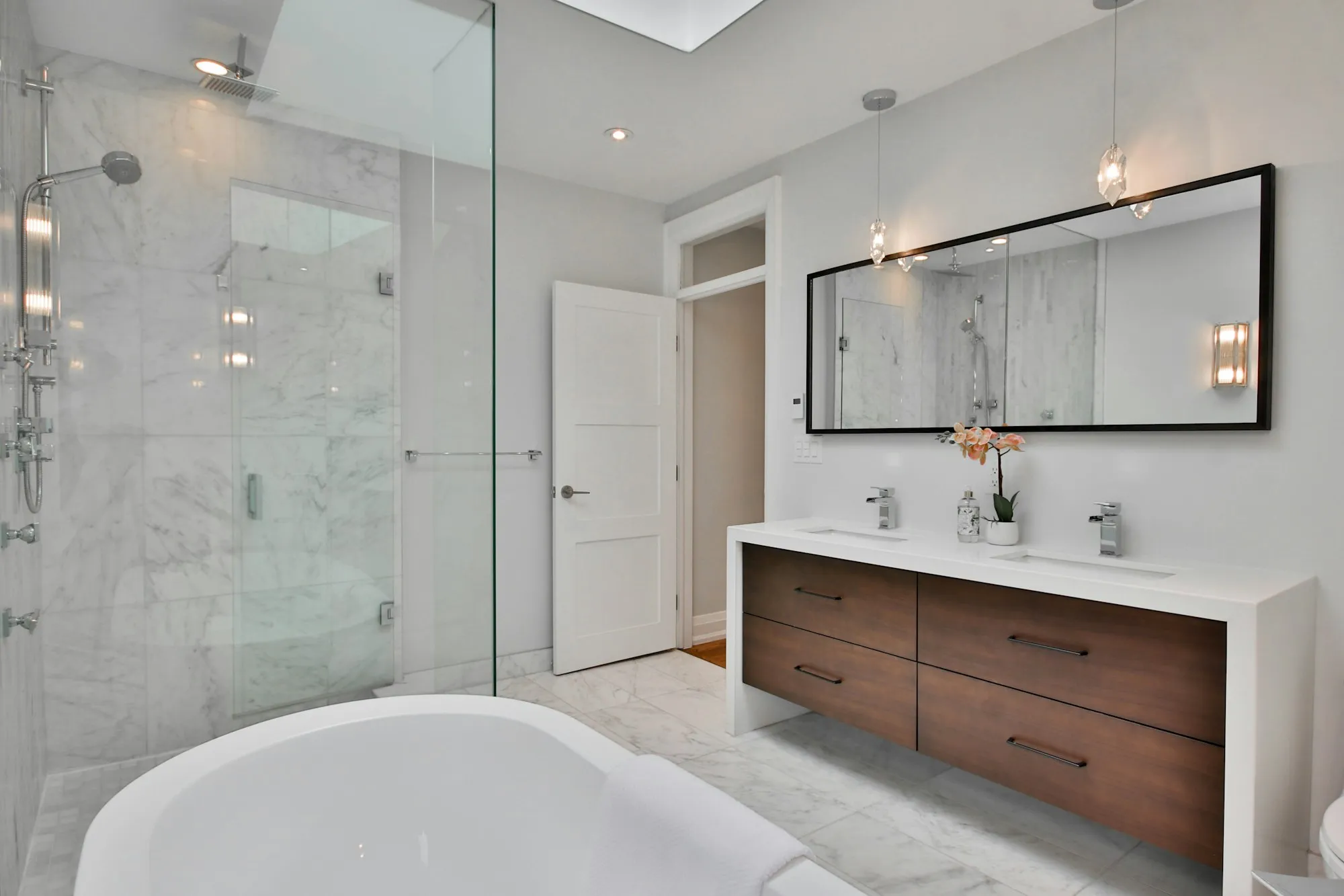 A floating timber vanity with a large mirror against marble tiling