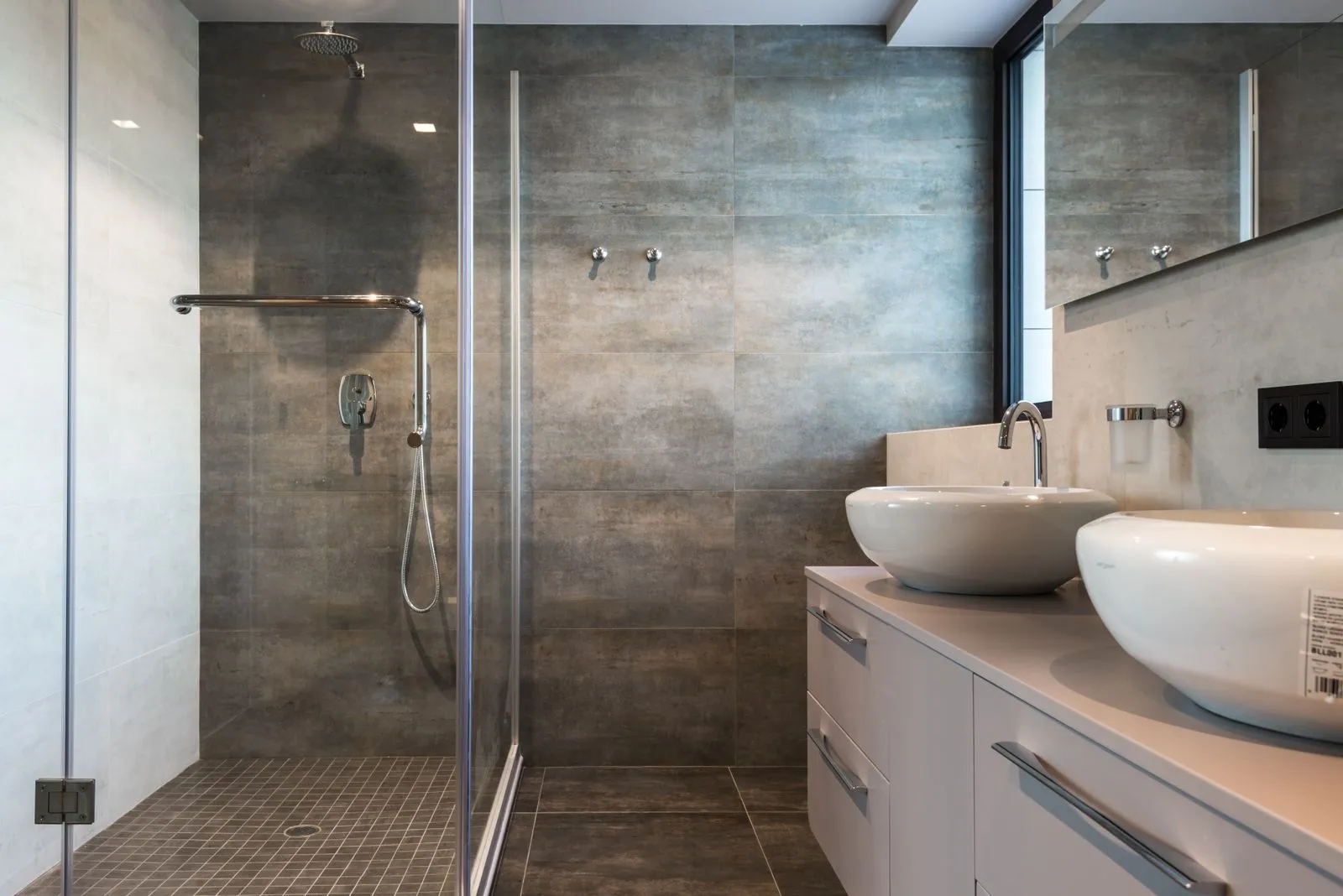 A stone clad walk in shower with frameless glass in a Cottesloe home