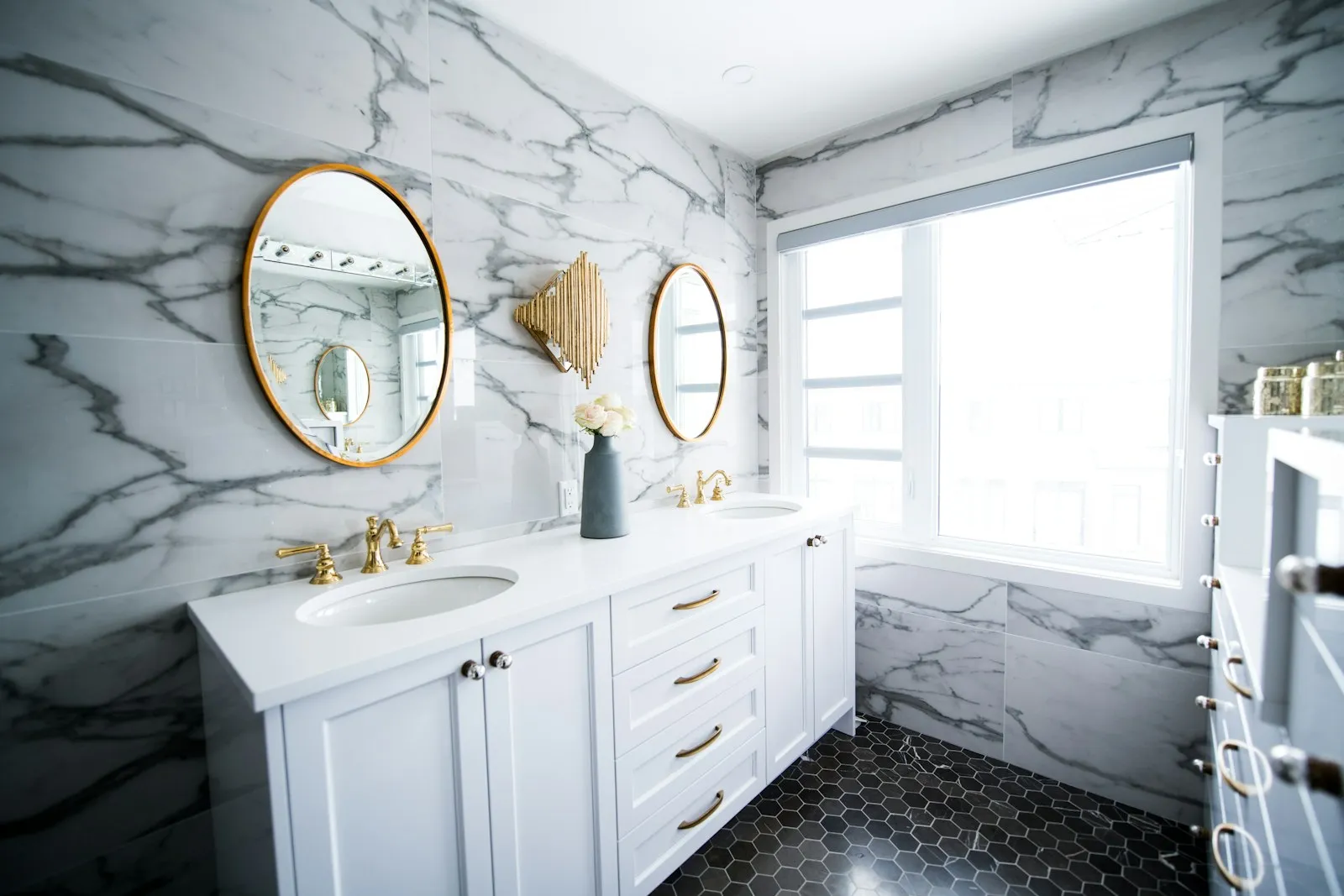 A double stone vanity with round mirrors and brass tapware in a Subiaco ensuite